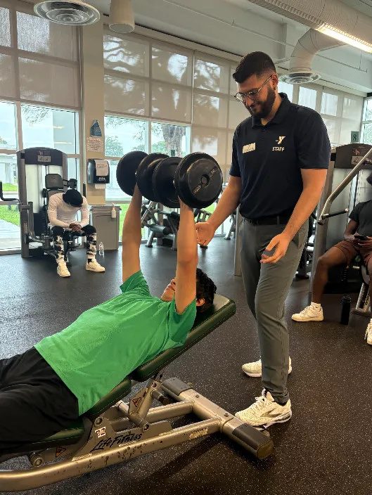 Boy lifting weights with Instructor